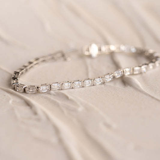 9k white gold  bracelet with diamond accents on a beige fabric background