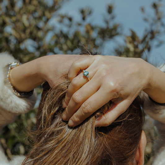 Woman with hands in hair wearing sustainable green diamond engagement ring aquamarine colour