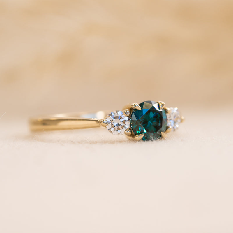 flat lay of tabitha by ethica diamonds dark  green moissanite ring with lab created side stones