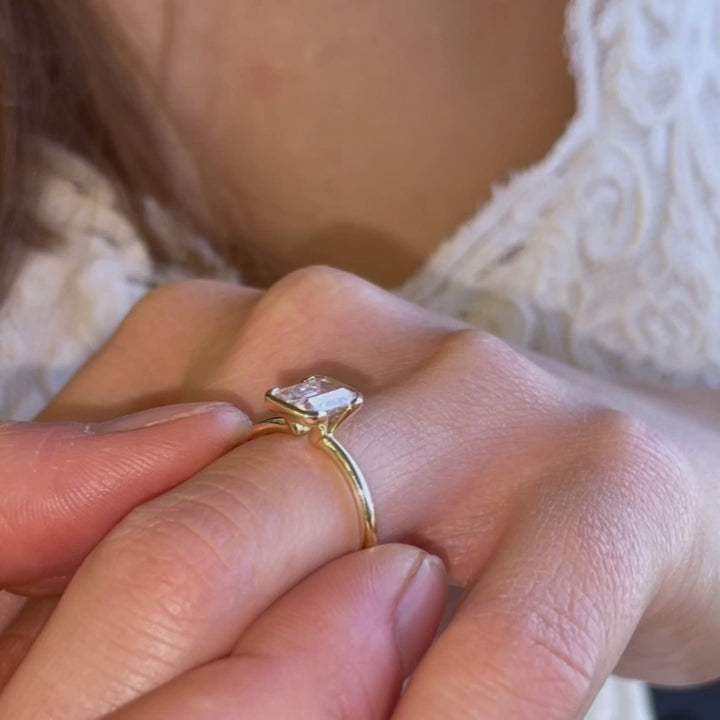 Video of model showcasing modern emerald engagement ring with slim gold band