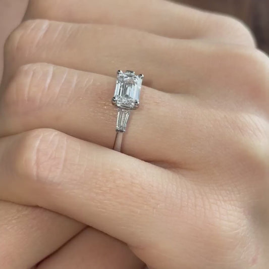video shows model wearing emerald cut east west setting ar deco engagement ring 