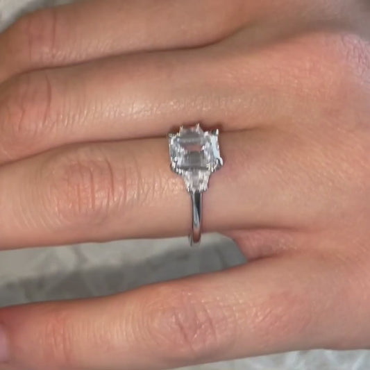 model wears trapezoid emerald diamond ring on Cornish beach 