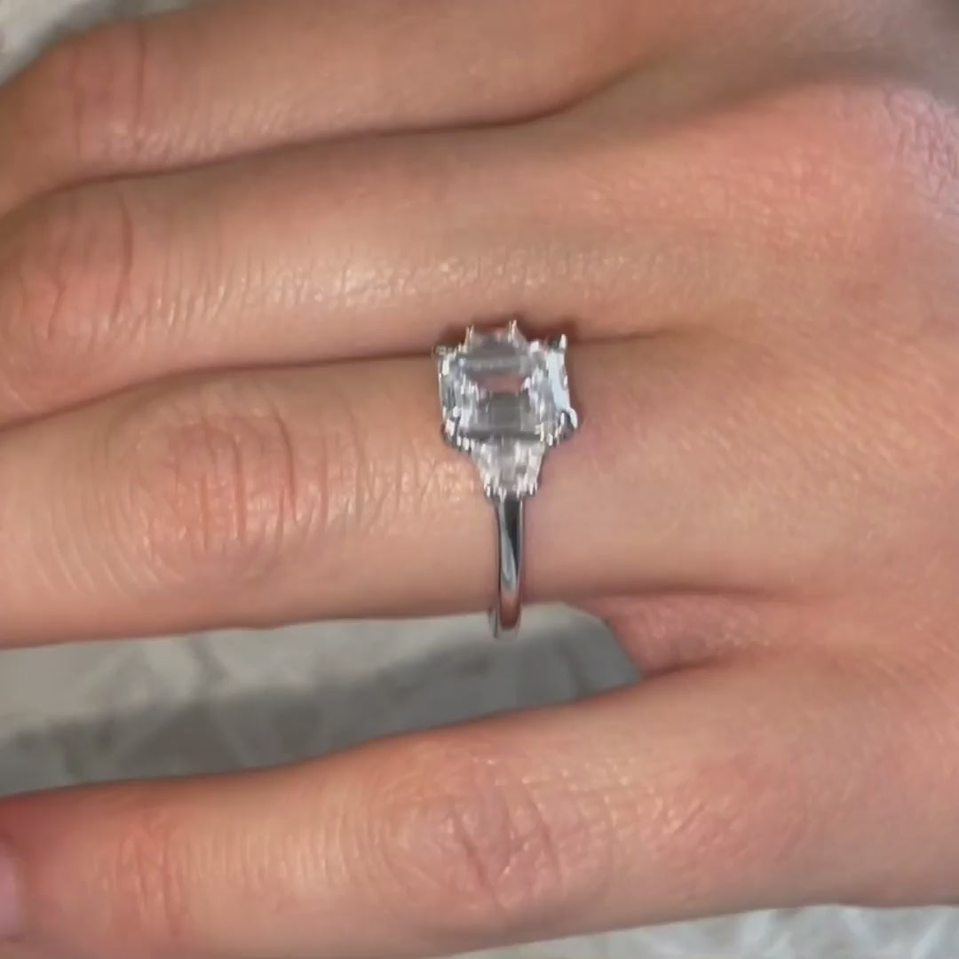 model wears trapezoid emerald diamond ring on Cornish beach 