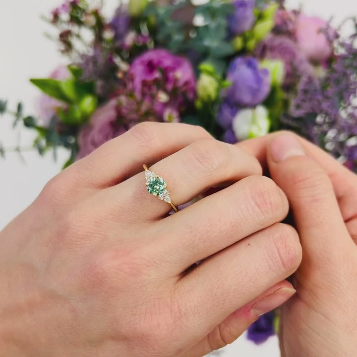 Model wears faint green diamond engagement ring in yellow gold with colourful flower bouquet