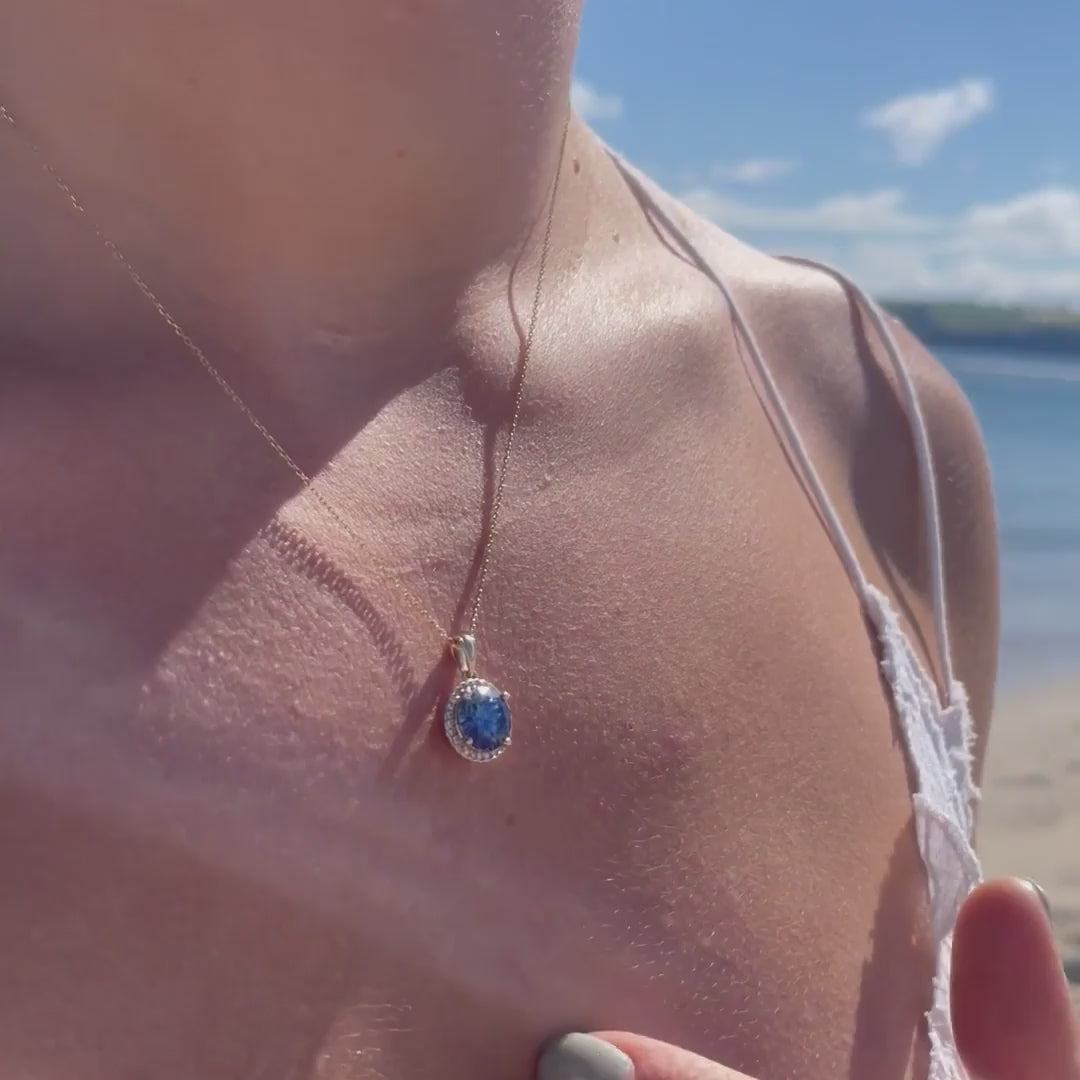 Model wearing a 2.81ct Round brilliant cut blue moissanite Pendant with the sea in the background