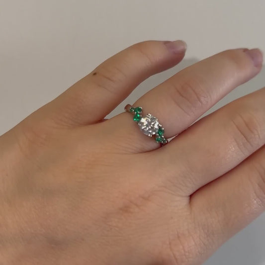 model wearing white gold diamond accented engagement ring in platinum with green side stones cornish made luxury jewellery
