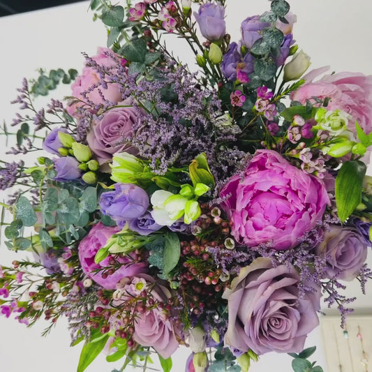 Model puts on a Cushion Blush Pink Solitaire ring with flowers in the background