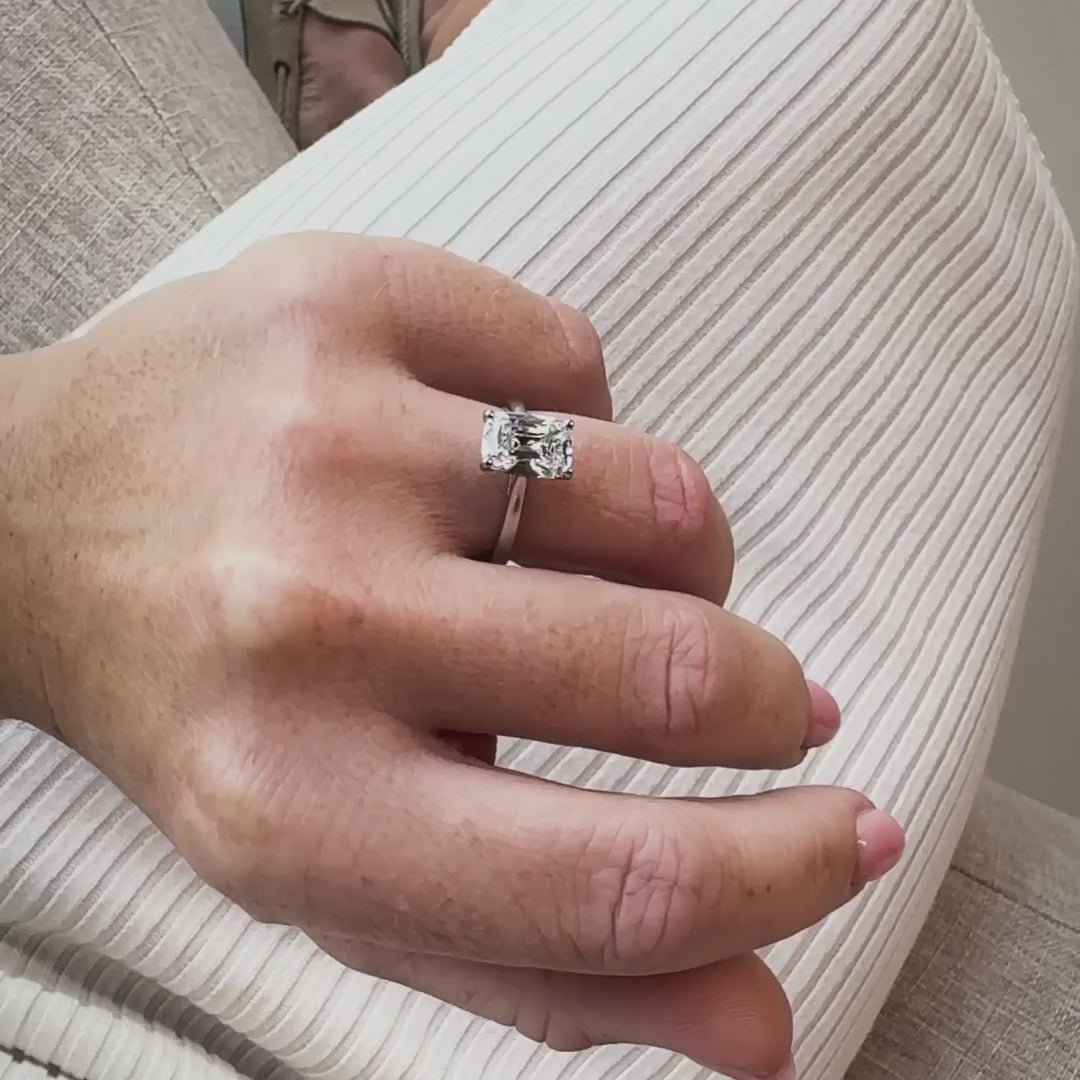 model wears elongated old mine cut diamond solitaire ring with pink nails and light pink skirt