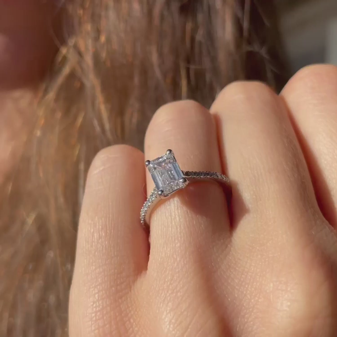 Model wears skinny minimalist large rectangular diamond engagement ring on sunny day showing hall of mirrors emerald