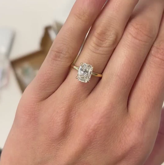 Model wears elongated cushion cut hidden halo engagement ring in yellow gold set with 4 claws - sustainable diamond jewellery made in cornwall