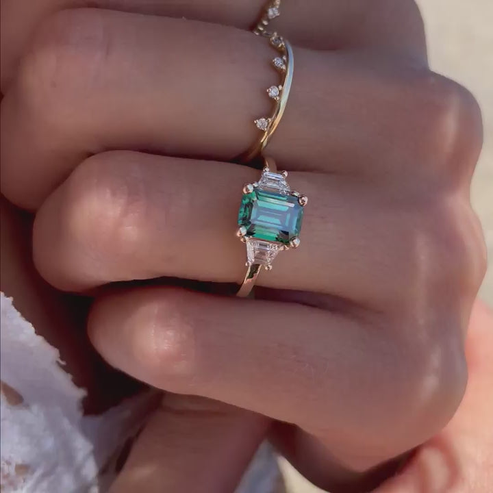 model wears green diamond ring on beach in cornwall with selection of lifestyle jewellery