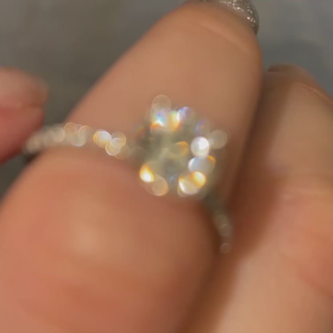 Model wears dainty 1 carat platinum diamond engagement ring with pavé diamond set shoulders and rounded tulip claws